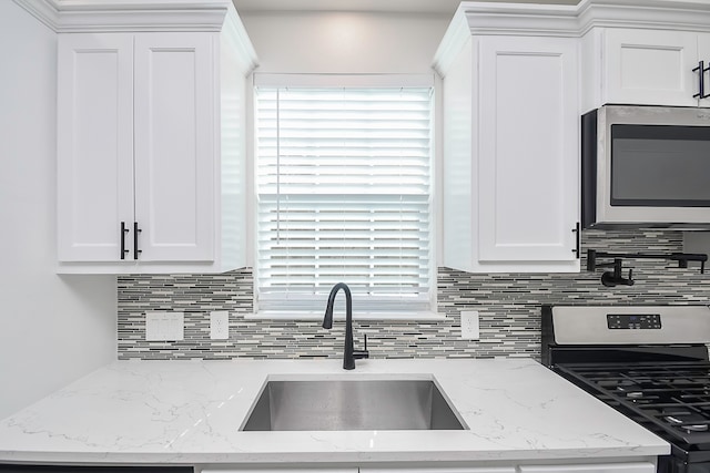 kitchen featuring range with gas stovetop, white cabinetry, and sink