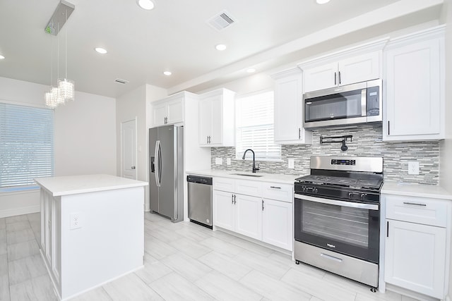 kitchen featuring appliances with stainless steel finishes, white cabinetry, a kitchen island, and sink