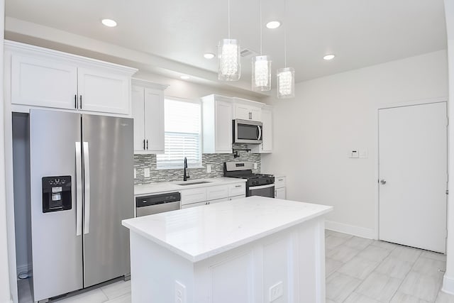 kitchen featuring appliances with stainless steel finishes, a kitchen island, sink, decorative light fixtures, and white cabinetry