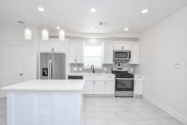 kitchen featuring white cabinetry, stainless steel appliances, light stone counters, decorative light fixtures, and a kitchen island