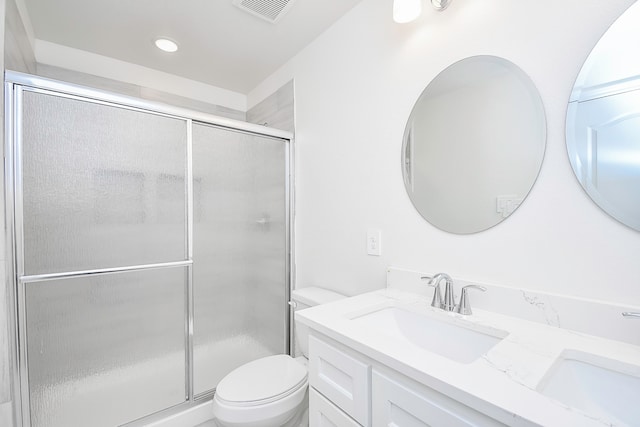 bathroom featuring vanity, a shower with shower door, and toilet