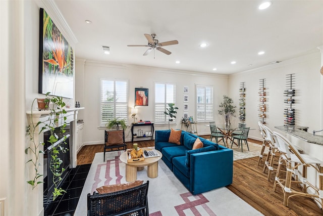 living room featuring a tile fireplace, crown molding, ceiling fan, and dark hardwood / wood-style floors