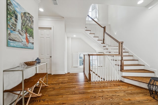 foyer entrance with crown molding, a high ceiling, and hardwood / wood-style flooring