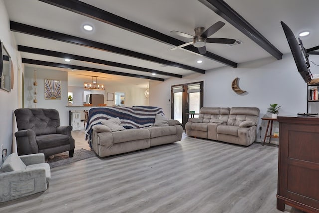 living room featuring beam ceiling, light hardwood / wood-style floors, and ceiling fan with notable chandelier