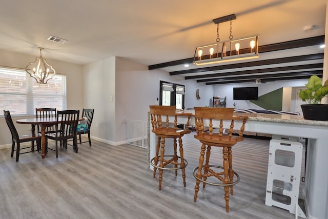 dining area with hardwood / wood-style flooring, a healthy amount of sunlight, and an inviting chandelier