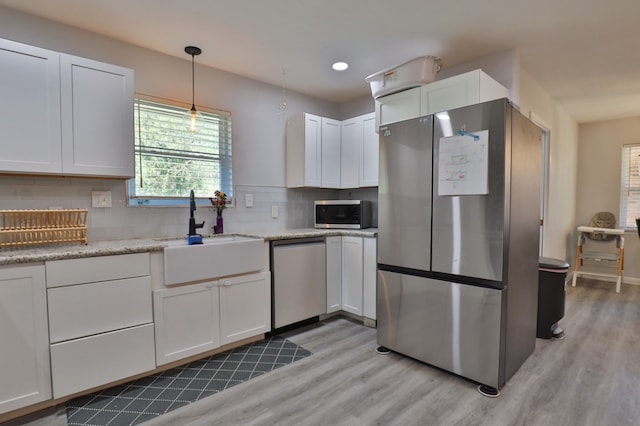 kitchen with decorative backsplash, stainless steel appliances, sink, light hardwood / wood-style flooring, and white cabinetry