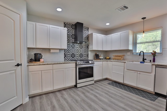 kitchen featuring electric stove, white cabinetry, sink, and wall chimney exhaust hood