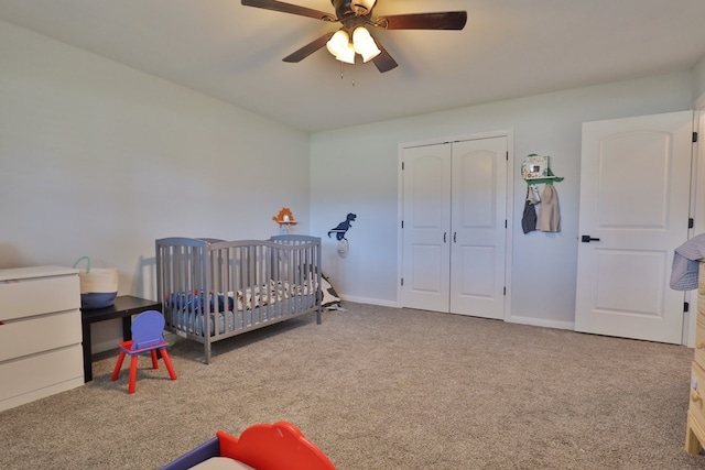 carpeted bedroom featuring ceiling fan, a closet, and a crib