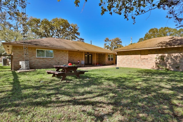 rear view of property with a yard and central air condition unit