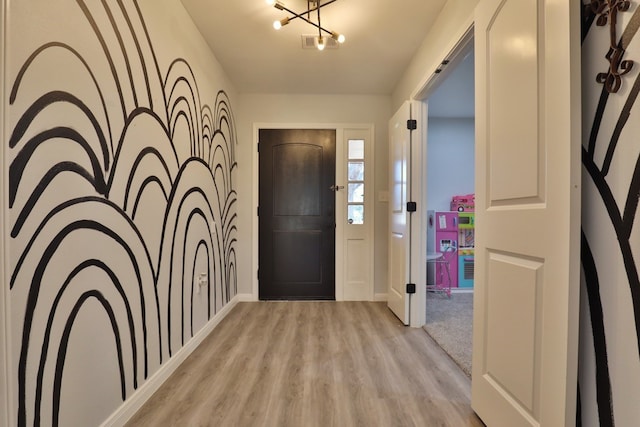 foyer with light hardwood / wood-style floors and an inviting chandelier