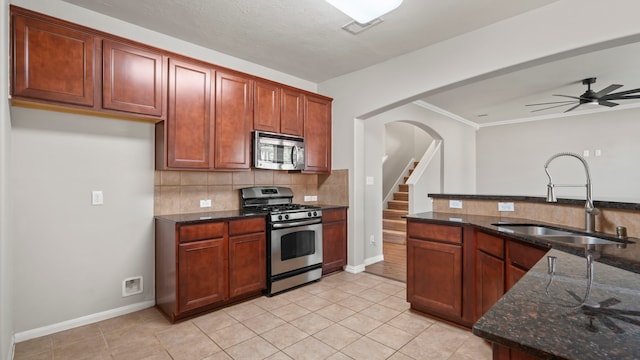 kitchen featuring ceiling fan, sink, tasteful backsplash, dark stone countertops, and appliances with stainless steel finishes