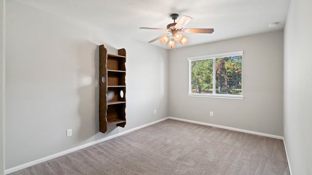 carpeted spare room with ceiling fan