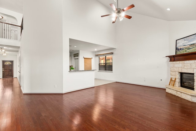 unfurnished living room with ceiling fan, dark hardwood / wood-style flooring, a fireplace, and high vaulted ceiling