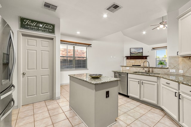 kitchen with appliances with stainless steel finishes, light stone countertops, sink, and a wealth of natural light