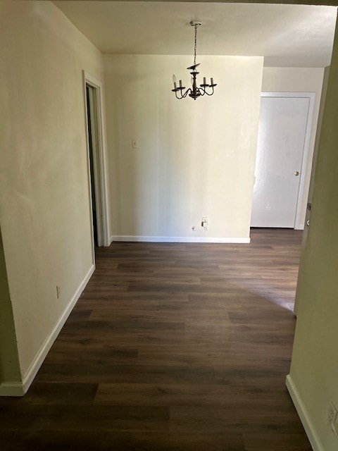 unfurnished dining area with a chandelier and dark wood-type flooring