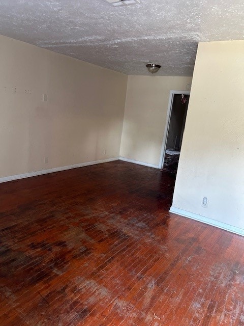 spare room featuring a textured ceiling and dark hardwood / wood-style flooring