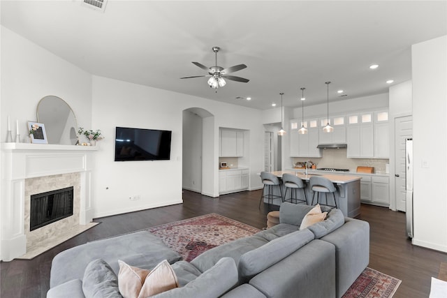 living room featuring sink, dark hardwood / wood-style flooring, a fireplace, and ceiling fan