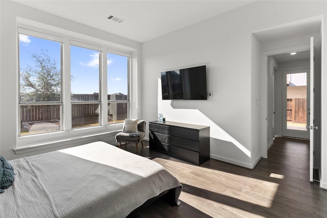 bedroom with multiple windows and dark wood-type flooring