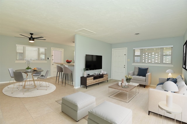 living room featuring ceiling fan, light tile patterned floors, and a textured ceiling