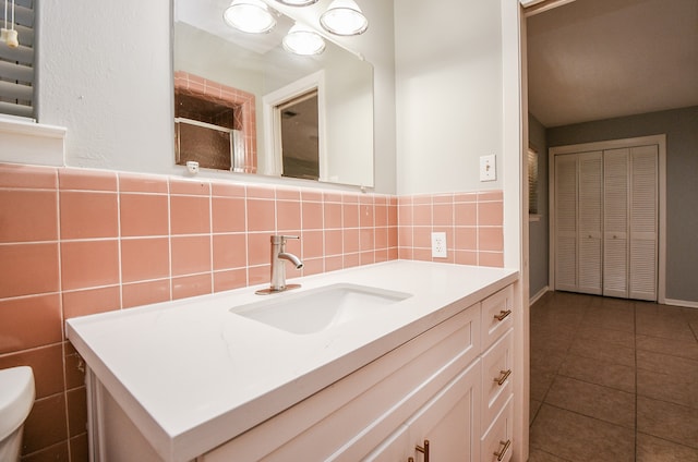 bathroom with tile patterned floors, radiator, vanity, tile walls, and toilet