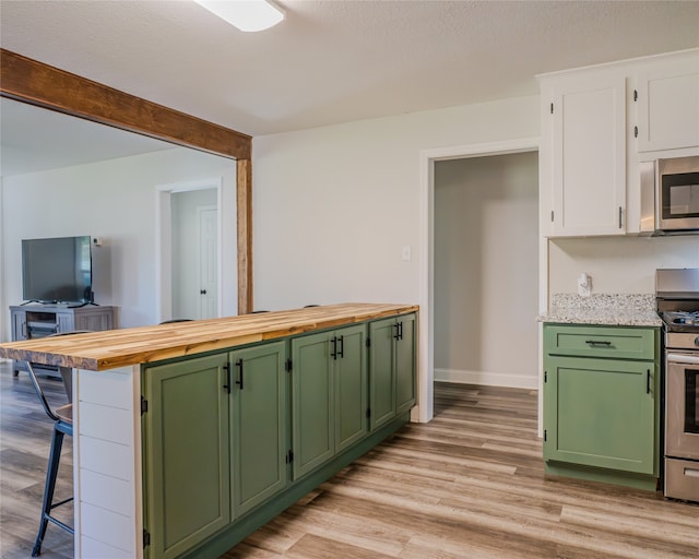 kitchen featuring stainless steel appliances, green cabinets, white cabinetry, light hardwood / wood-style floors, and a breakfast bar