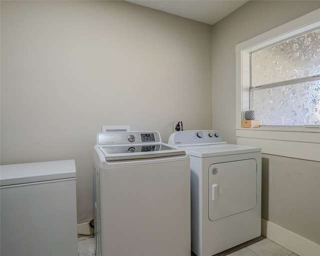 clothes washing area with light tile patterned floors and washer and clothes dryer