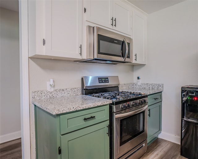 kitchen featuring hardwood / wood-style flooring, appliances with stainless steel finishes, light stone countertops, and white cabinetry