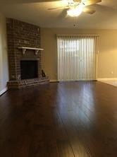 unfurnished living room with ceiling fan, wood-type flooring, and a brick fireplace