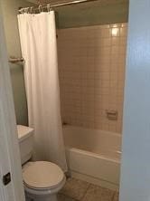 bathroom featuring shower / tub combo, toilet, and tile patterned floors