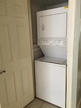 laundry area featuring light tile patterned floors and stacked washer / dryer