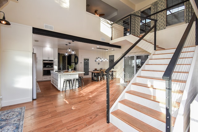 stairs with a towering ceiling and hardwood / wood-style flooring