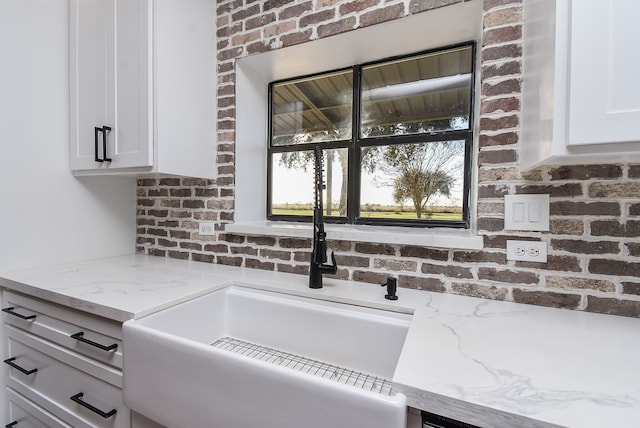 interior details featuring white cabinets and light stone counters