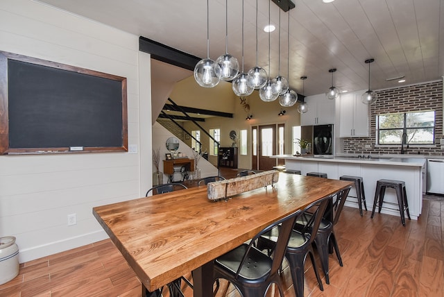 dining space with wood walls, light hardwood / wood-style floors, and sink