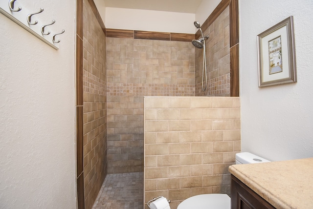 bathroom with tiled shower, vanity, and toilet