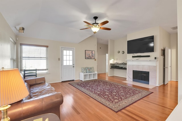 living room with a tile fireplace, vaulted ceiling, light hardwood / wood-style flooring, and ceiling fan