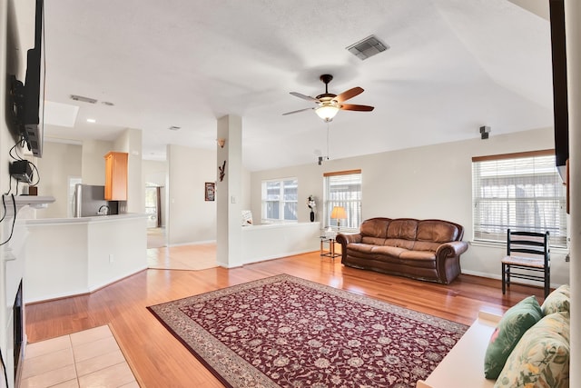 living room featuring ceiling fan, lofted ceiling, and light wood-type flooring