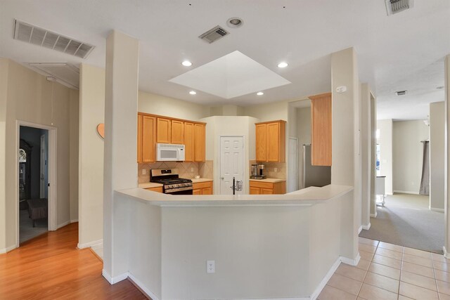 8226 Point Pendleton Dr, Tomball, TX 77375 - kitchen with white microwave, stainless steel range with gas stovetop, light countertops, backsplash, and baseboards