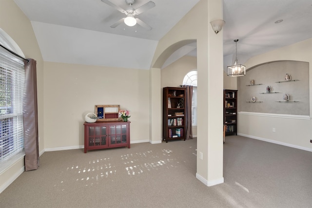 carpeted living room featuring ceiling fan with notable chandelier and vaulted ceiling