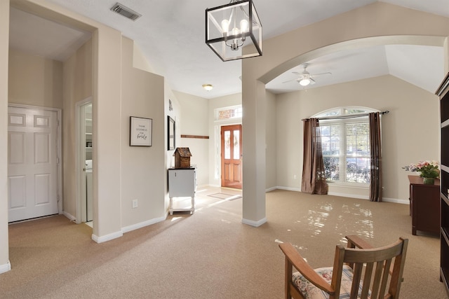 carpeted foyer with ceiling fan with notable chandelier and vaulted ceiling