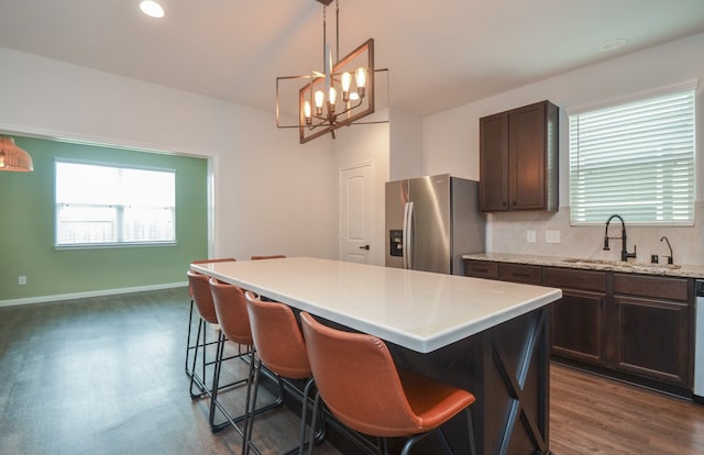 kitchen featuring dark wood-type flooring, sink, pendant lighting, stainless steel fridge with ice dispenser, and a center island