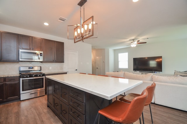 kitchen with a center island, stainless steel appliances, dark hardwood / wood-style flooring, pendant lighting, and a breakfast bar