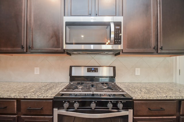 kitchen featuring backsplash, dark brown cabinets, light stone countertops, and stainless steel appliances