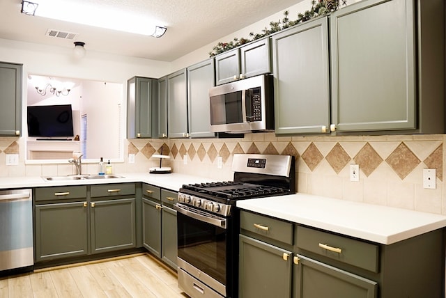 kitchen with tasteful backsplash, sink, light hardwood / wood-style flooring, and appliances with stainless steel finishes