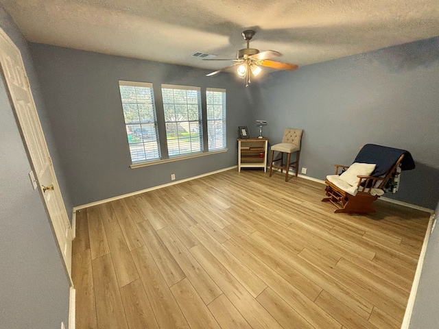 unfurnished room featuring ceiling fan, light hardwood / wood-style flooring, and a textured ceiling