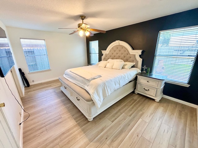 bedroom with ceiling fan, light wood-type flooring, and a textured ceiling