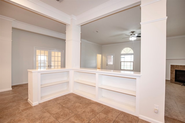 carpeted empty room with plenty of natural light, ceiling fan, crown molding, and decorative columns