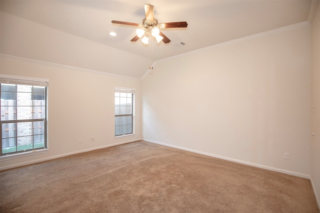 carpeted spare room featuring ceiling fan, vaulted ceiling, and ornamental molding