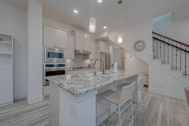 kitchen featuring light stone countertops, appliances with stainless steel finishes, tasteful backsplash, decorative light fixtures, and white cabinetry