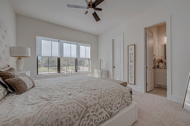 bedroom featuring light carpet, ensuite bath, and ceiling fan