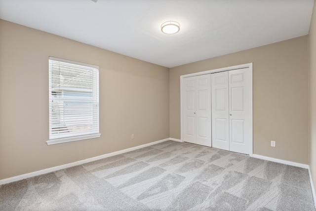 unfurnished bedroom with light carpet and a closet